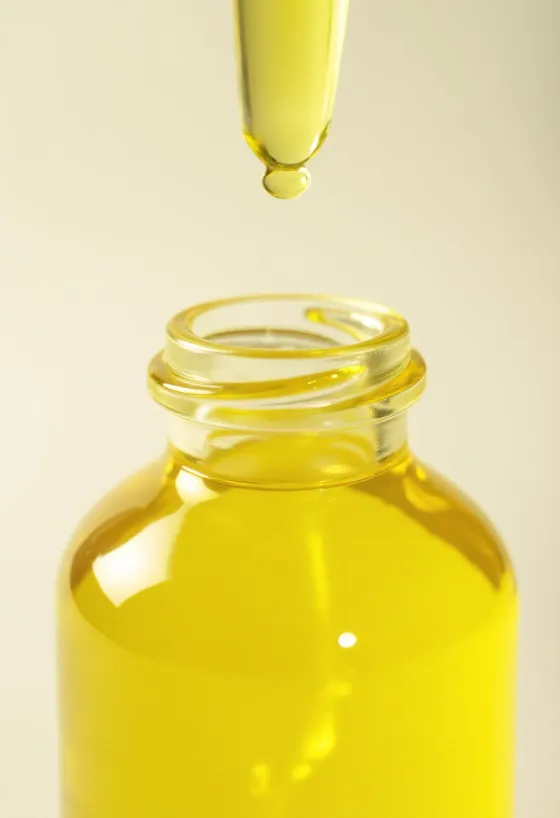 Limunovo ulje u bočici, uz svježe kriške limuna i koricu