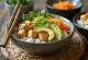 Poké bowl s tofuom, serviran sa svježim povrćem i avokadom, posut sezamom.