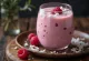 Probiotički kefir s kokosom i malinama poslužen u čaši, pored svježih malina i ribanog kokosa