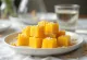 Žarko žute kocke mango barfija posute listićima badema.