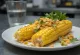 Elote poslužen s prženim kukuruzom, cheddar sirom i kriškama limete
